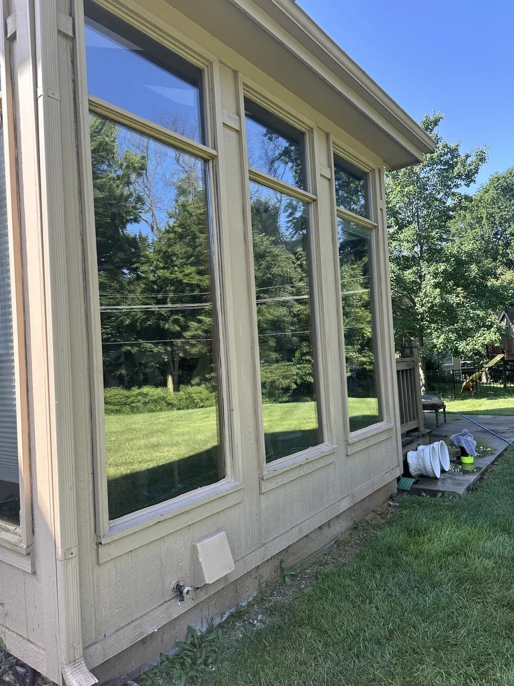 Exterior window cleaning on a sunroom in Olathe, trees reflected in the glass